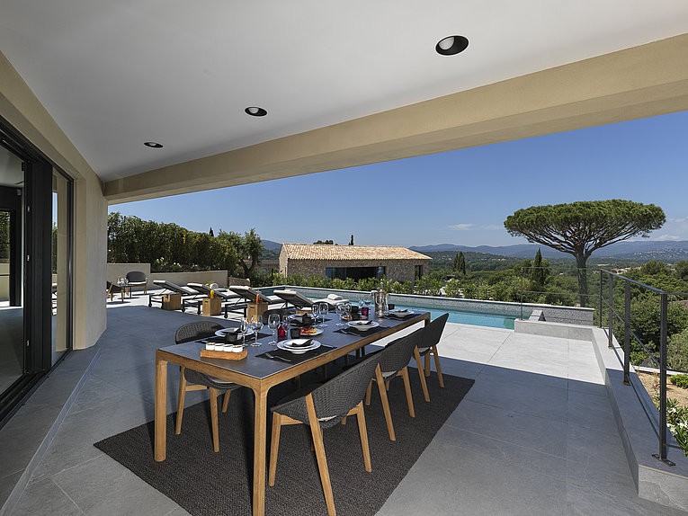 Althoff Villa Belrose in St. Tropez Côte d'Or Terrasse mit Pool und gedecktem Tisch und Stühlem im Sommer und Meerblick