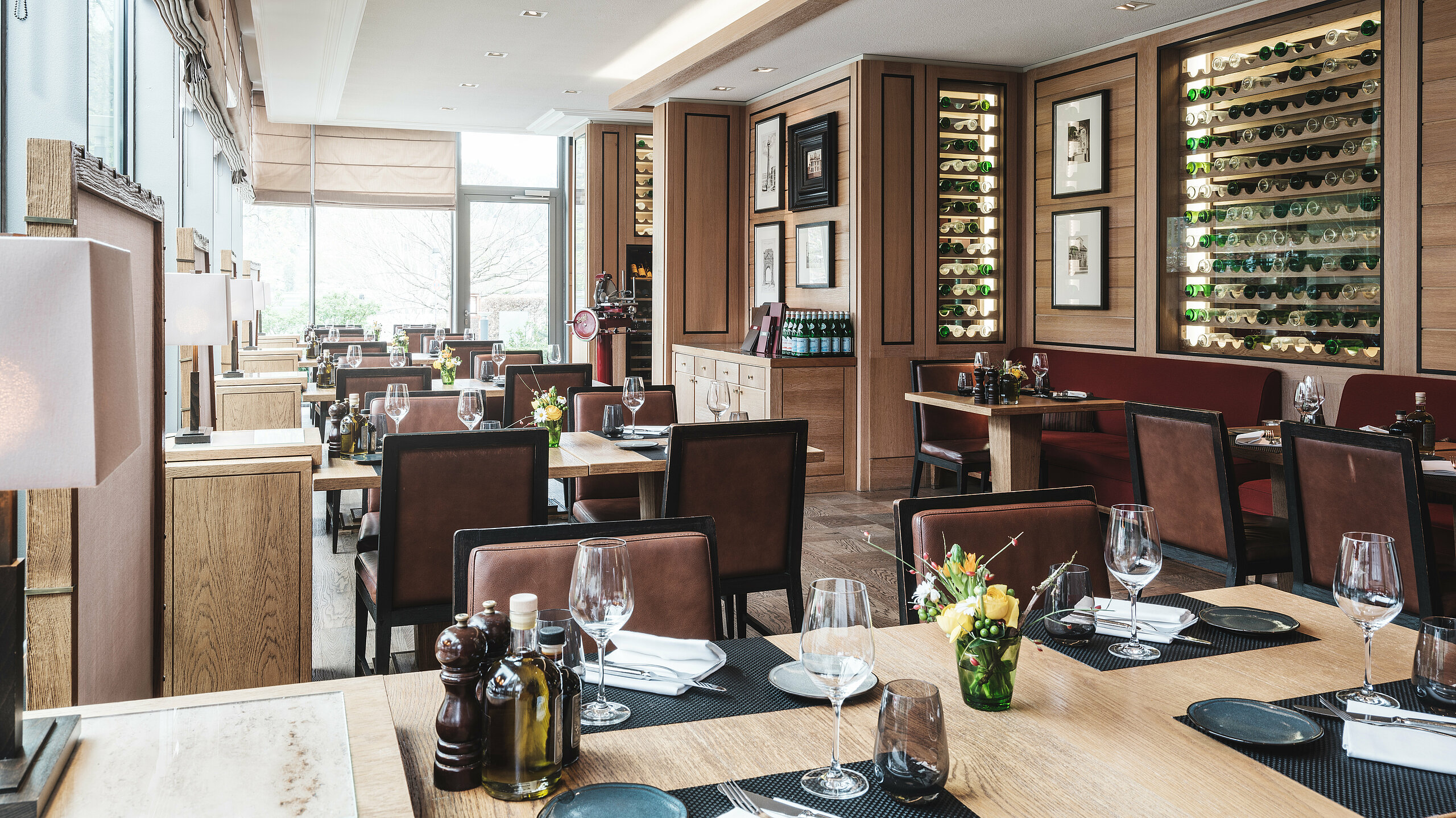 Althoff Seehotel Überfahrt Restaurant Il Barcaiolo Innenberreich mit gedeckten Tischen und dem Weinregal