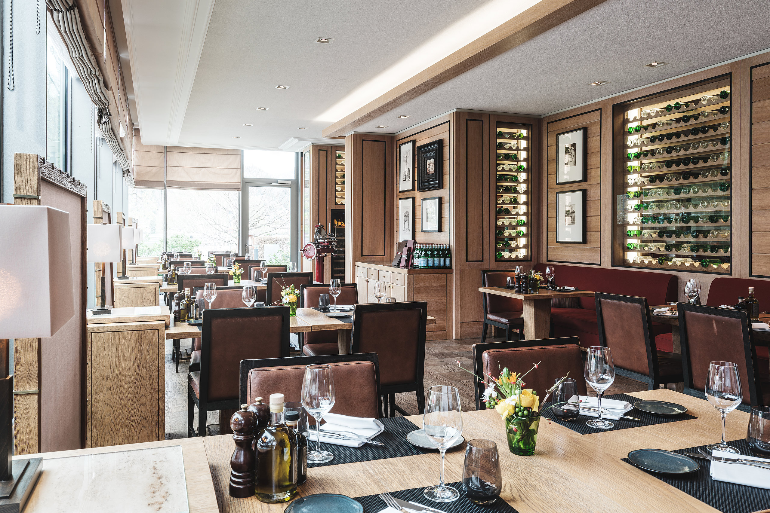 Althoff Seehotel Überfahrt Restaurant Il Barcaiolo Innenberreich mit gedeckten Tischen und dem Weinregal